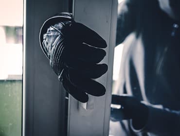 Eine Person mit schwarzen Handschuhen öffnet eine Tür oder ein Fenster.