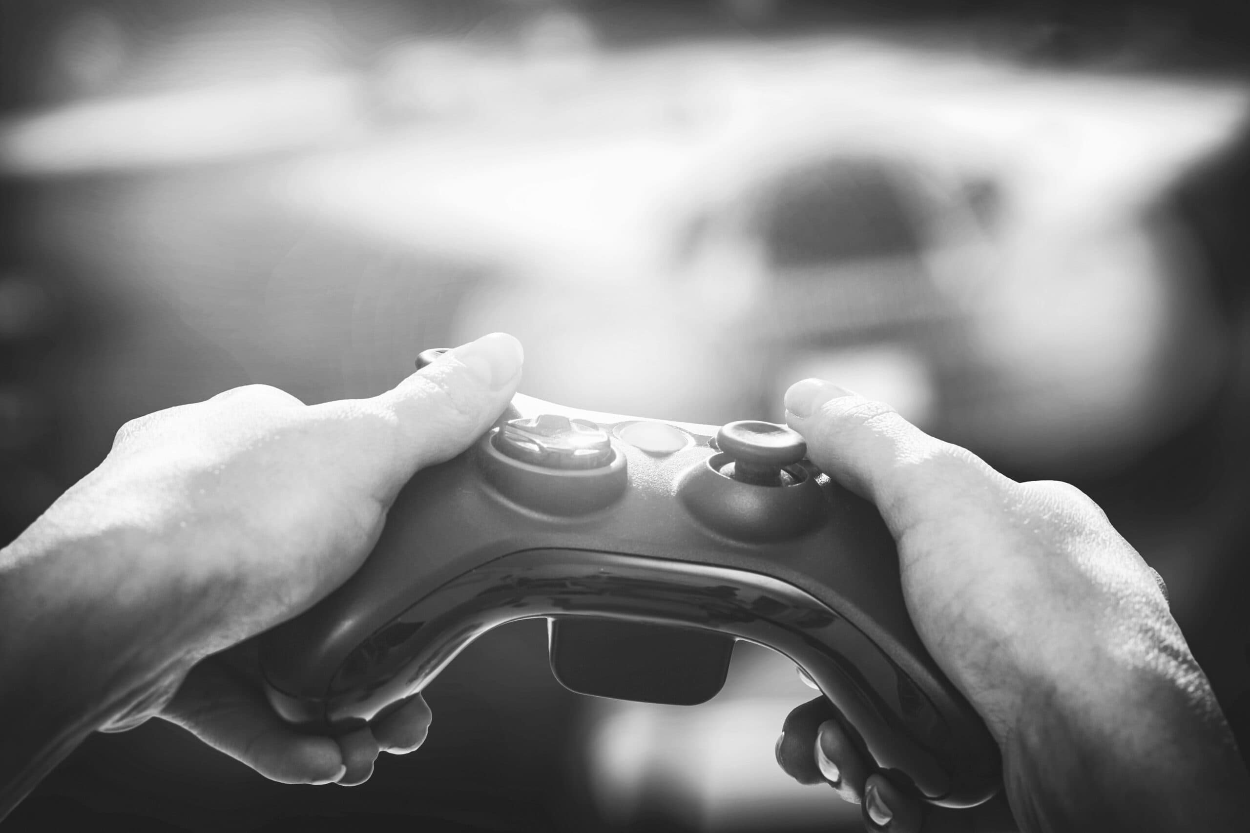 Nahaufnahme von zwei Händen, die einen Videospiel-Controller halten. 
