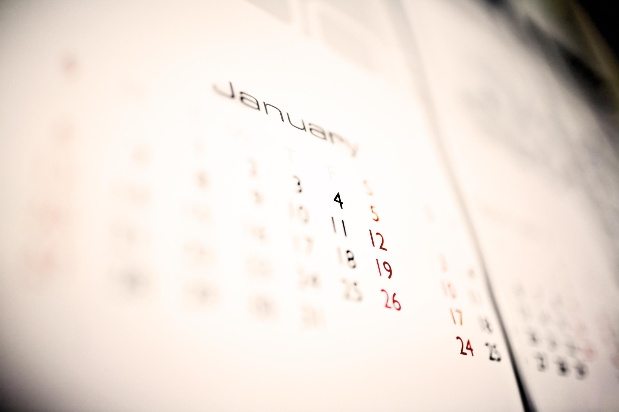 Verschwommenes Bild eines Kalenders, der den Monat Januar zeigt. Die Daten 4, 11, 18 und 25 sind schwarz markiert, während die Daten 5, 12, 19 und 26 rot markiert sind