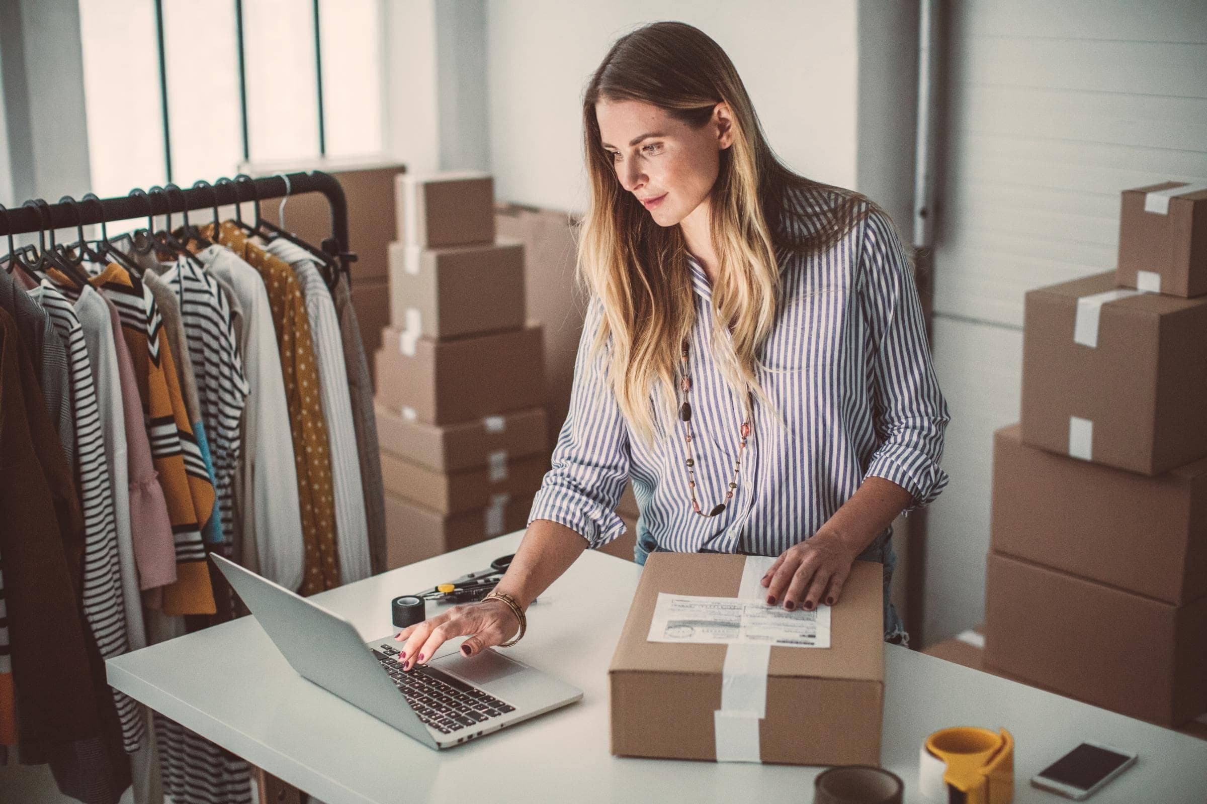 Onlineshop-Versicherung von Hiscox: Onlineshop-Betreiberin arbeitet in ihrem Warenlager am Laptop