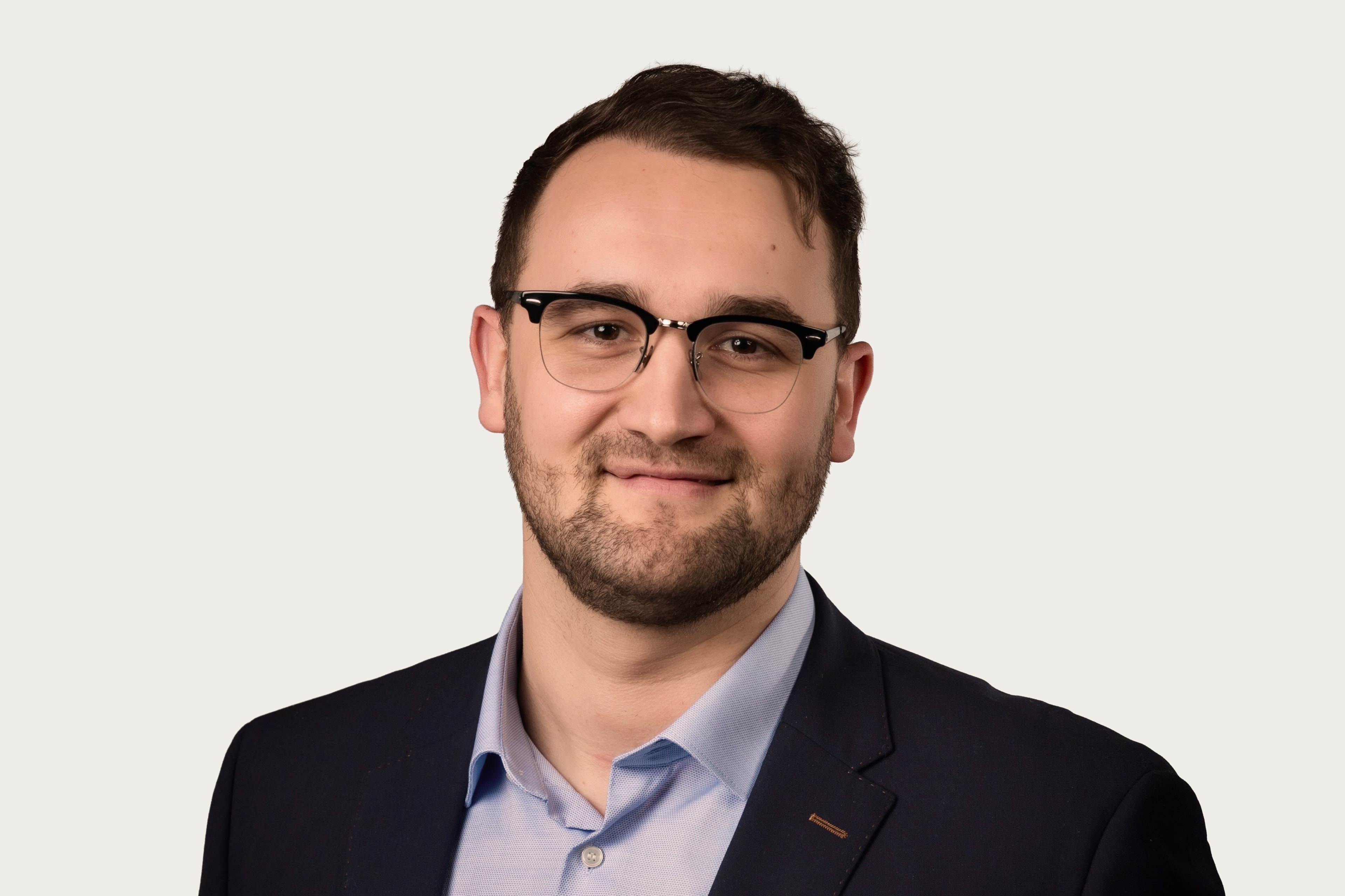 Klemens Lemke, Underwriting Manager Cyber bei Hiscox, trägt eine Brille und einen Anzug und lächelt in die Kamera