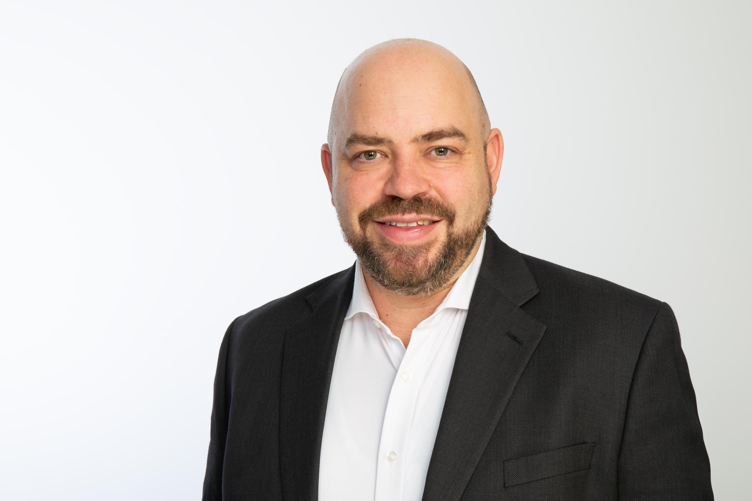  Tobias Wenhart von Hiscox trägt einen Anzug und Hemd vor weißem Hintergrund. 