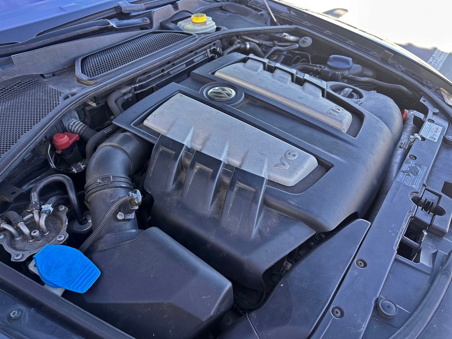 Nahaufnahme des Motorraums eines Fahrzeugs mit Schwerpunkt auf einem V6-TDI-Motor. Der Bereich scheint gut gepflegt zu sein, mit sichtbaren Komponenten, Schläuchen und Abdeckungen.