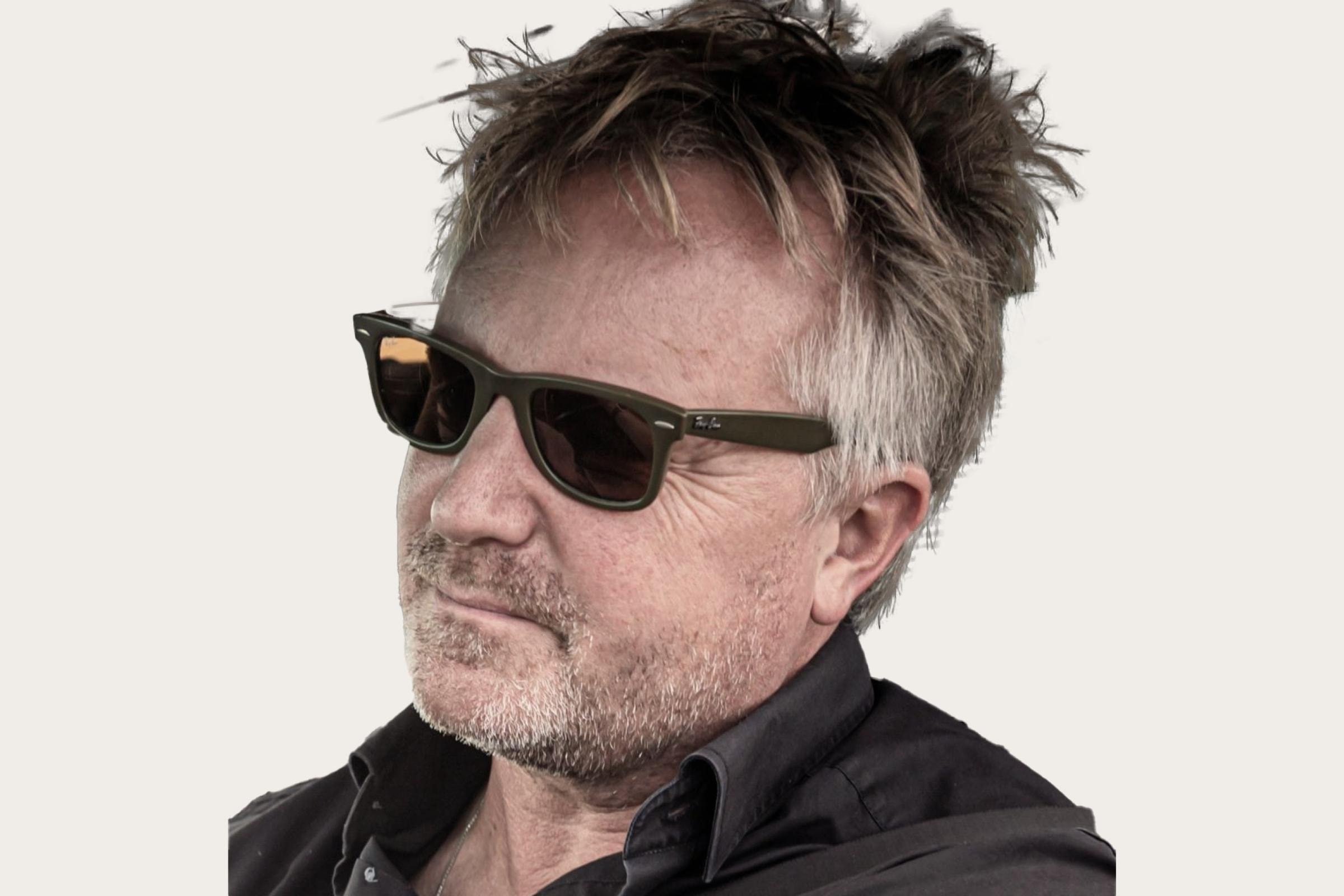 Jens Tanz, ein Gastautor bei Hiscox, ist ein Man mit grauen Haaren und Sonnenbrille und er trägt ein dunkles Hemd und hat zerzaustes Haar.