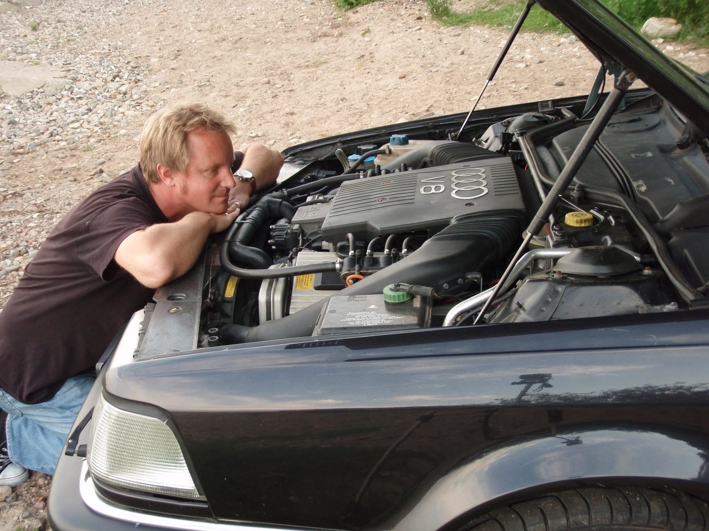Jens Tanz blickt in den Motorraum des schwarzen Audi v8 auf den Motor.