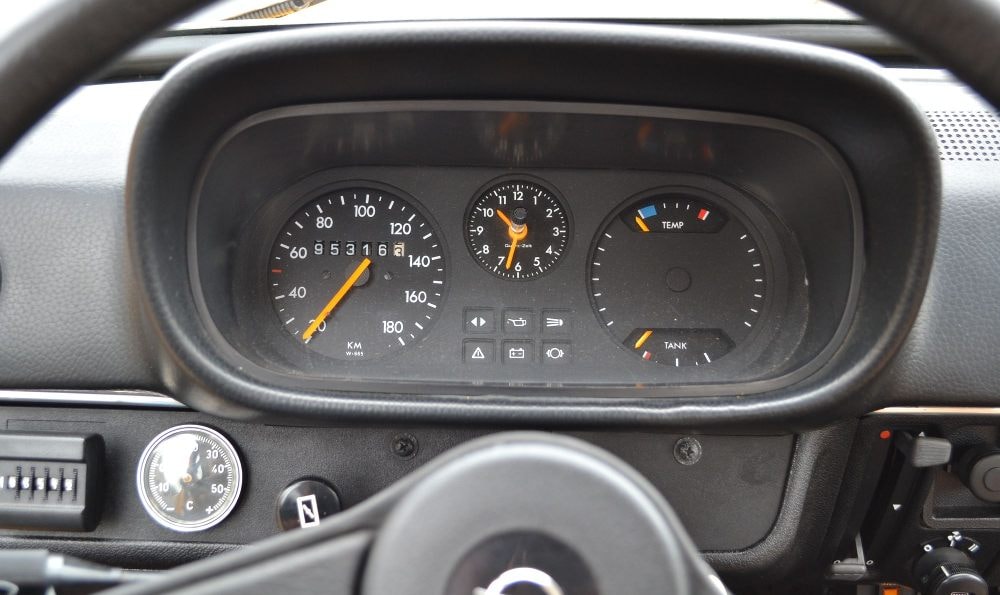 Armaturenbrett eines Autos mit Tachometer, Drehzahlmesser, Kraftstoffanzeige, Motortemperaturanzeige und einer analogen Uhr.