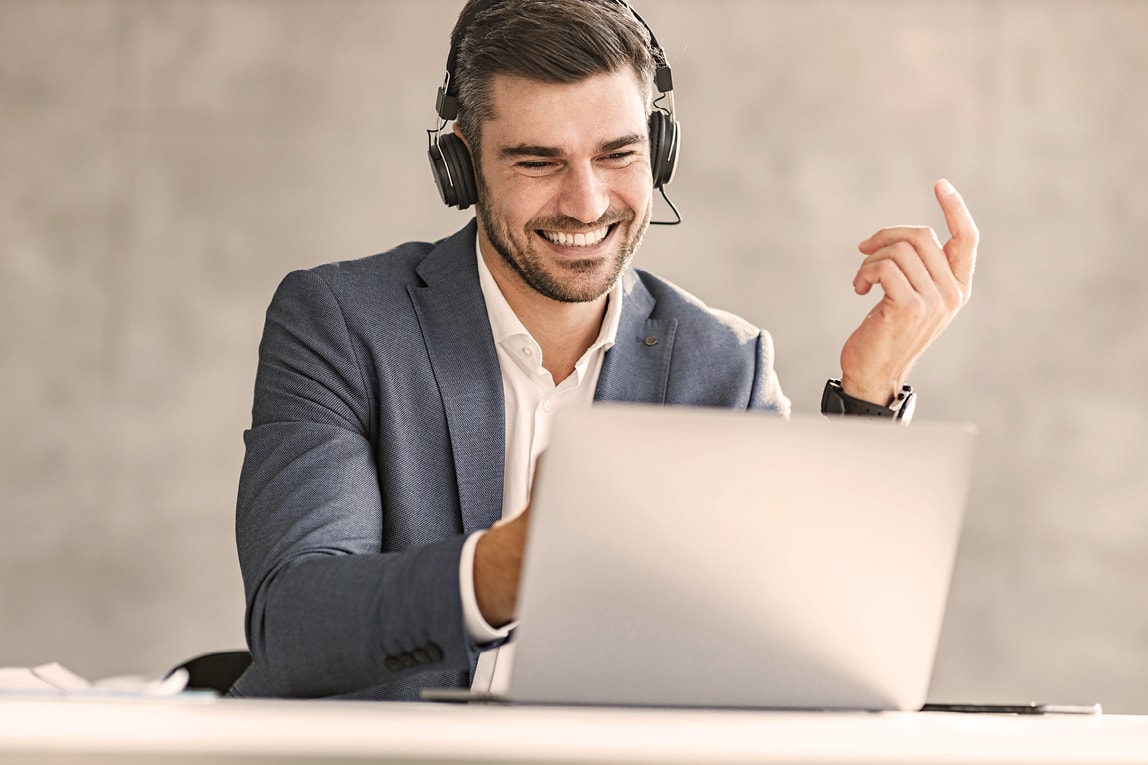 Ein Mann in Anzug hat Kopfhörer auf und ist in einem Online-Meeting