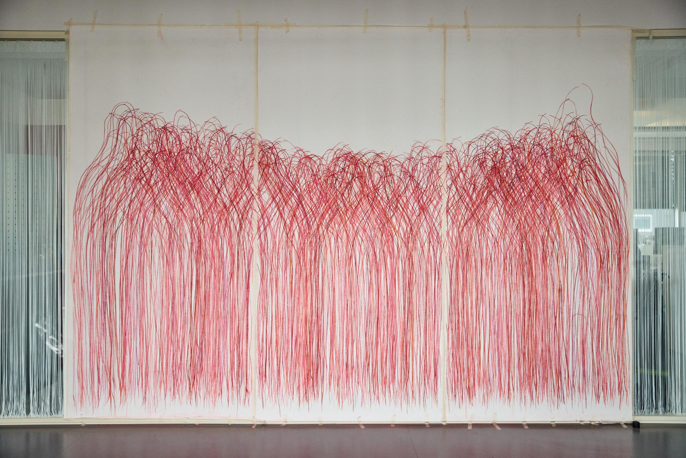 Auf einem großen Wandbild sind die mit rötlichen Kreiden gezeichneten Umrisse von mehreren hundert Menschen zu sehen.