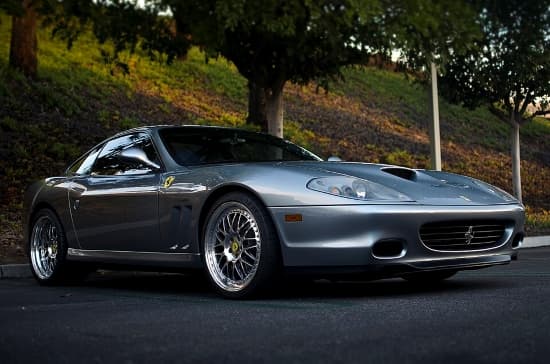 Ferrari 550 Maranello in silber vor Park-Hintergrund in schräger Frontansicht