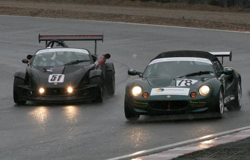 Zwei Autos, Lotus Elise in Grün und Lotus 340R in Schwarz, auf Rennstrecke in Frontansicht