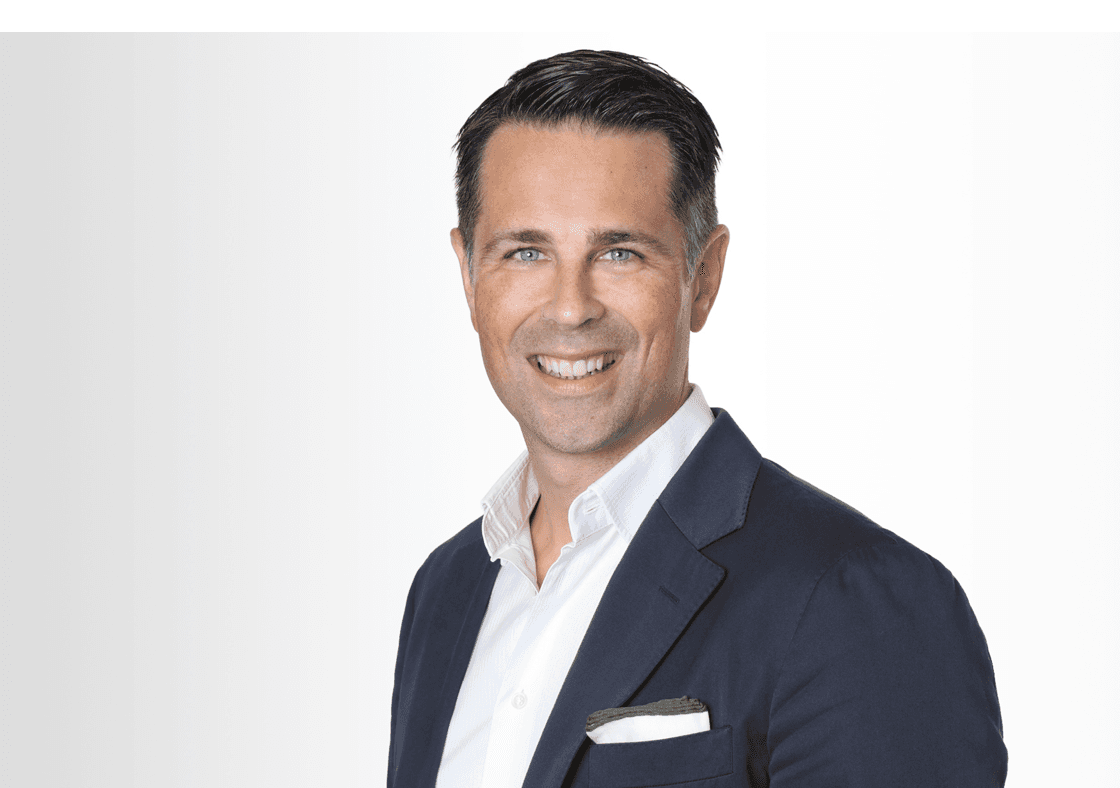 Der Deutschland-Chef von Hiscox Tim Bethge trägt ein dunkles Sakko und weißes Hemd und lächelt in die Kamera