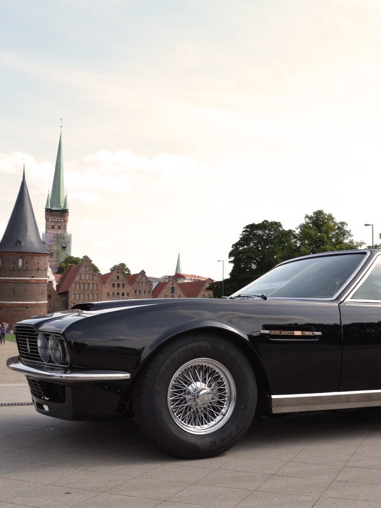 Schwarzer Aston Martin vor dem historischen Holstentor in Lübeck, Deutschland