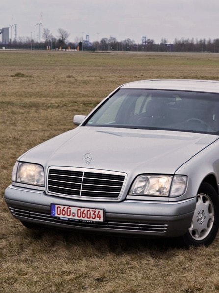 Frontansicht eines grauen Mercedes Benz w140 s320 parkend auf einer grünen Wiese mit Wald im Hintergrund