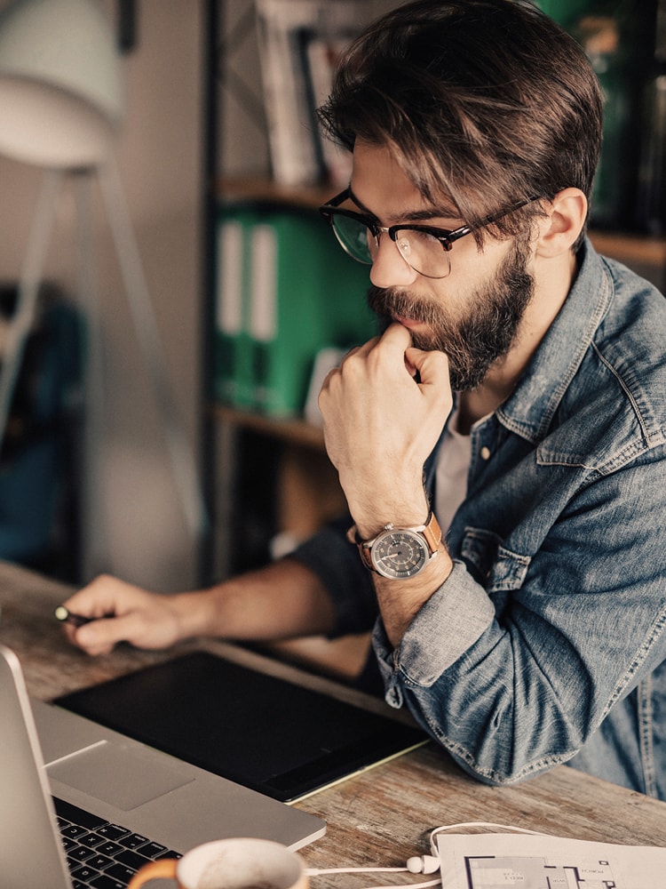 Ein junger Mann in Jeanshemd arbeitet an seinem Laptop