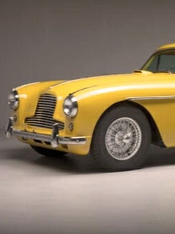 Ein gelber Aston Martin steht in einem Studio, umgeben von neutralen Hintergründen und professioneller Beleuchtung.