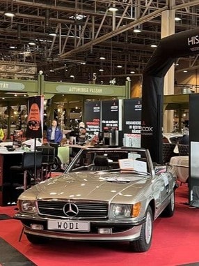 Blick auf den Messestand von Hiscox au der Oldtimer Fachmesse in Essen 2024mit Blick au ein Oldtimer-Model und Messeaufsteller