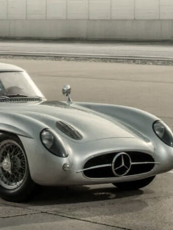 Ein klassischer silberner Mercedes-Benz 300 SLR Uhlenhaut Coupé, der auf einer Betonfläche geparkt ist.