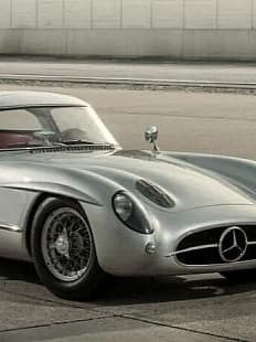Ein klassischer silberner Mercedes-Benz 300 SLR Uhlenhaut Coupé, der auf einer Betonfläche geparkt ist.