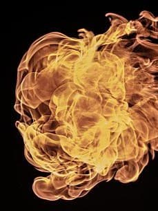 Ein dynamisches und komplexes Flammenmuster vor einem schwarzen Hintergrund. Die Flammen wirbeln und kräuseln sich, wobei sie verschiedene Gelb-, Orange- und Rottöne zeigen.