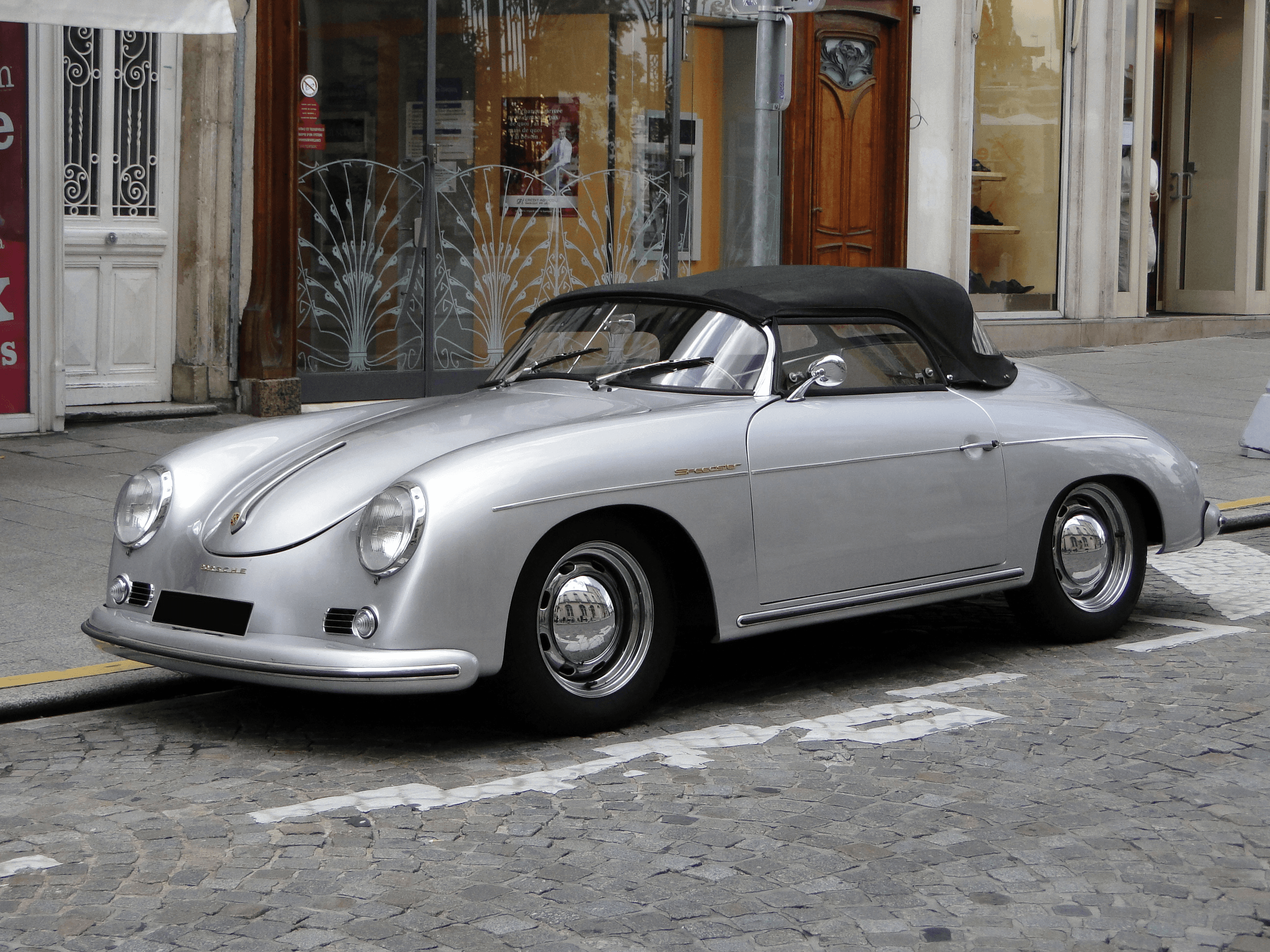 Klassischer marineblauer Sportwagen Porsche 365 Speedster mit beigem Verdeck, Chromakzenten und runden Scheinwerfern vor schwarzem Hintergrund, der Eleganz ausstrahlt.