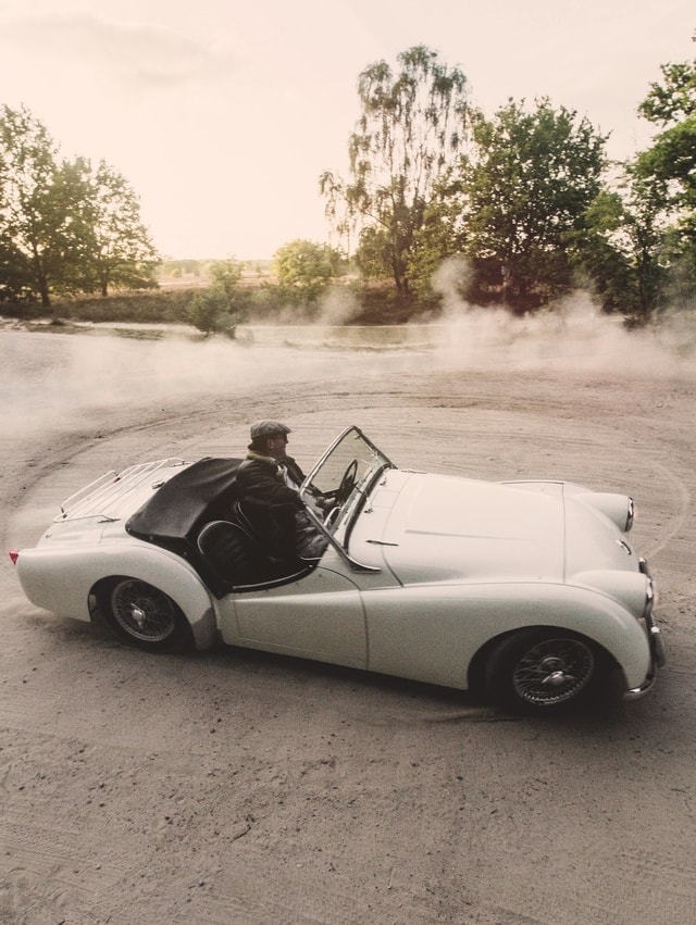 Ein Fahrer driftet in seinem Cabrio-Oldtimer über eine freie Fläche
