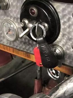 Klassischer Autoinnenraum mit Zündschloss, eingestecktem Schlüssel und rotem Anhänger.