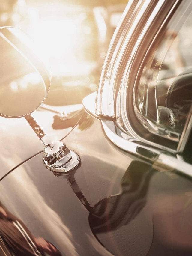 Oldtimer-Versicherung von Hiscox: Nahaufnahme des Seitenspiegels eines klassischen Autos mit spiegelnder Sonne