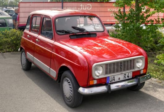 Ein alter roter Renault R4 GLT steht an einem sonnigen Tag im Freien. Es hat ein kantiges Design, Chromdetails und einen klassischen Look, der Nostalgie und Charme ausstrahlt.