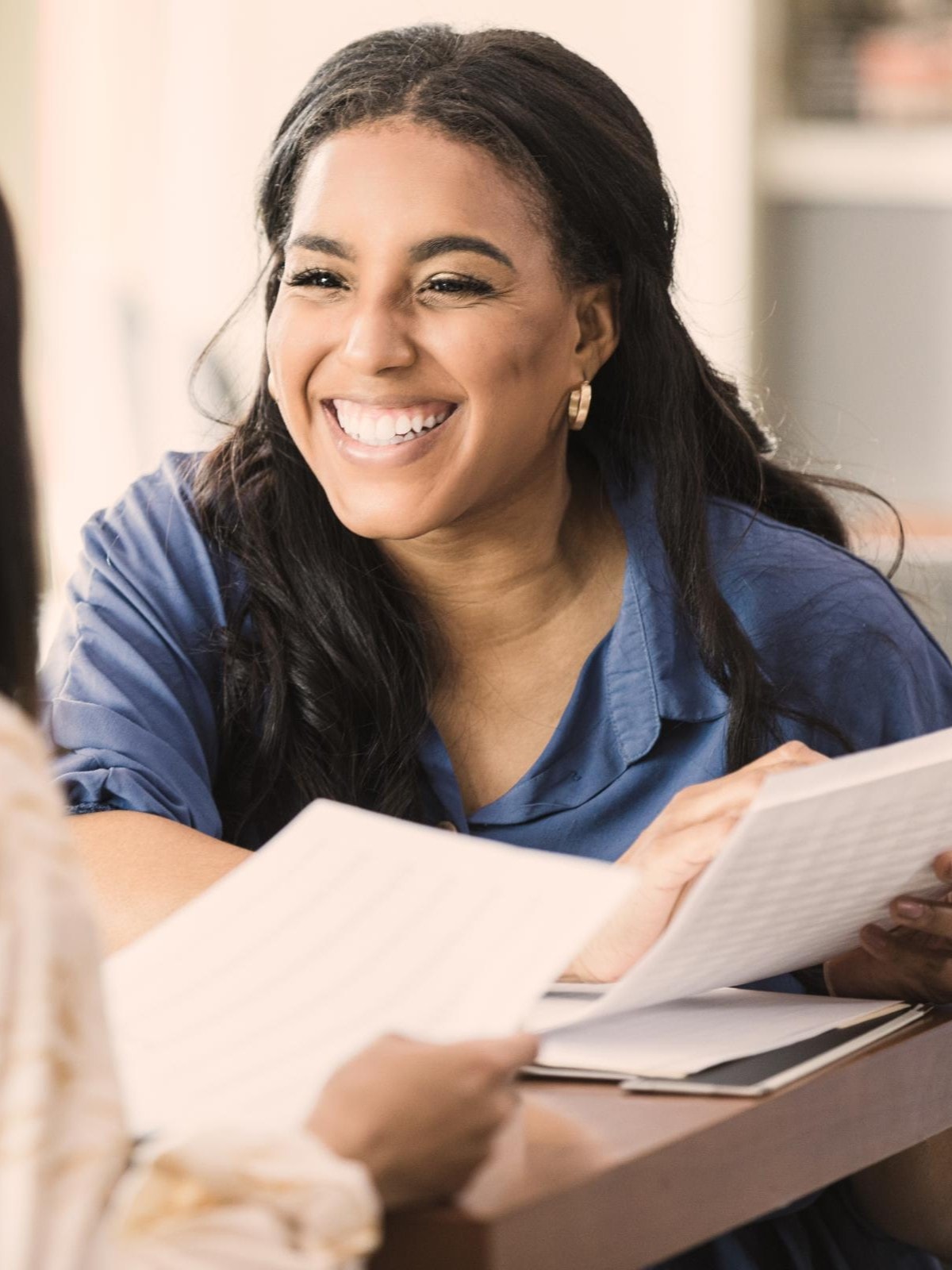 Freundliches Gespräch zwischen zwei Geschäftsfrauen: Austausch von Dokumenten in professioneller Umgebung