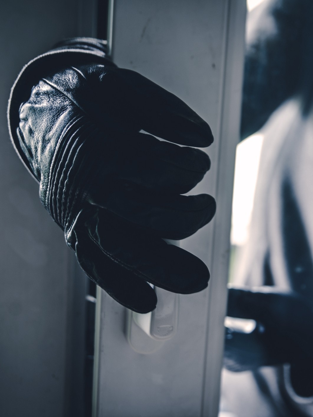 Einbruch: Kriminelle Person mit Handschuhen versucht, eine Tür aufzuhebeln