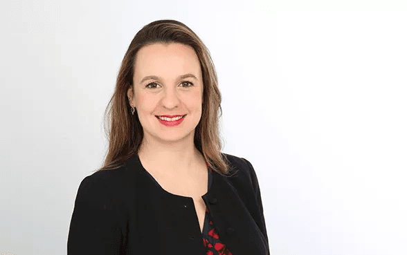 Alina Sucker mit rotem Lippenstift und schwarzer Blazer bei der Arbeit für Hiscox.