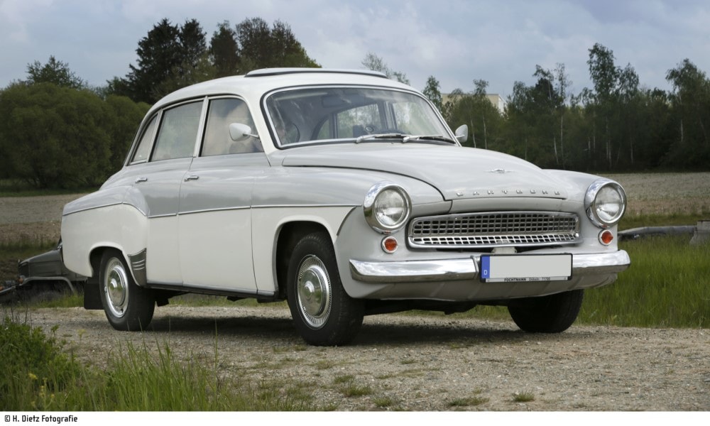 Der grau-weiße Oldtimer Wartburg 312 steht am Straßenrand eines Feldes geparkt.