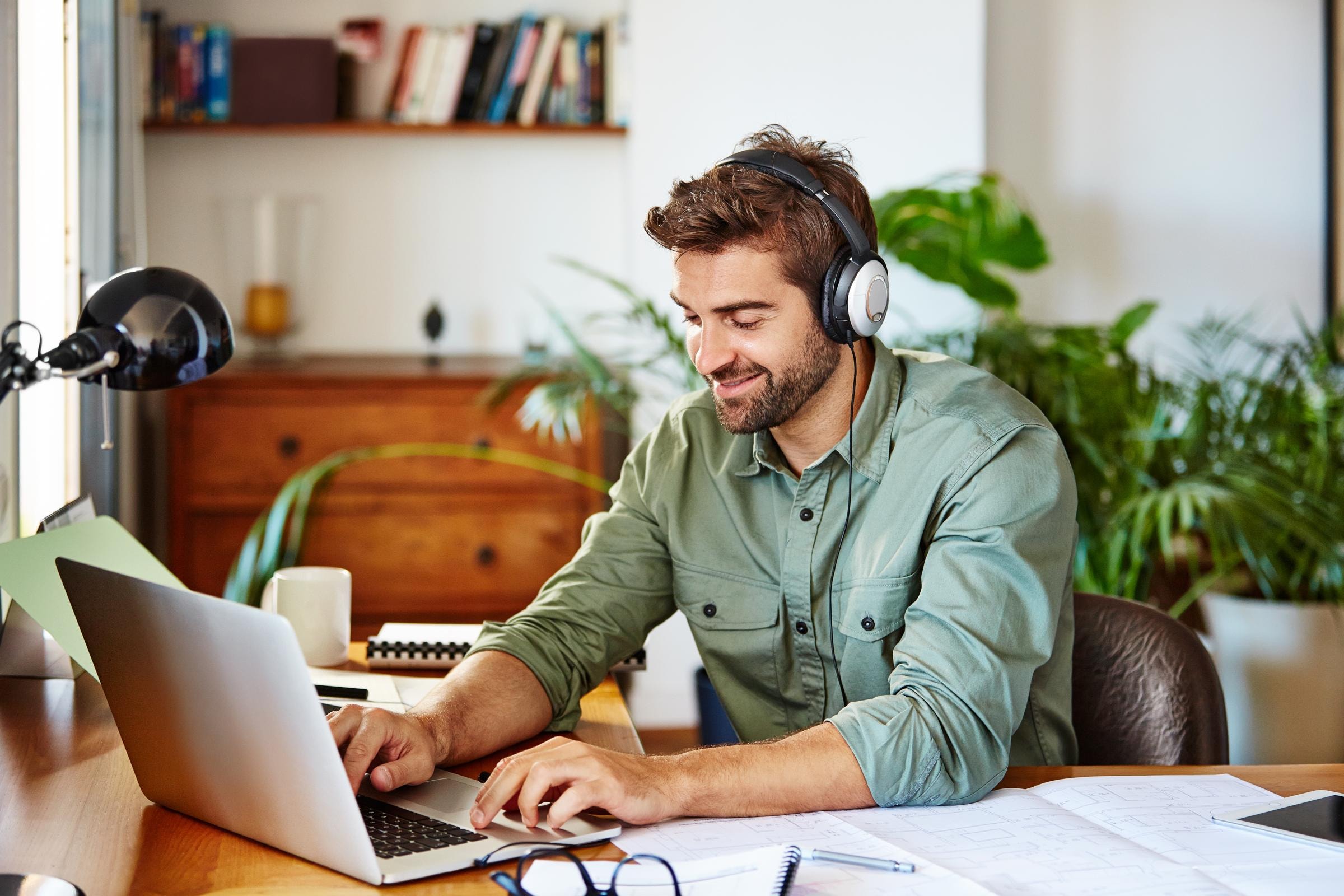 Ein junger Mann sitzt mit Kopfhörern vor seinem Laptop