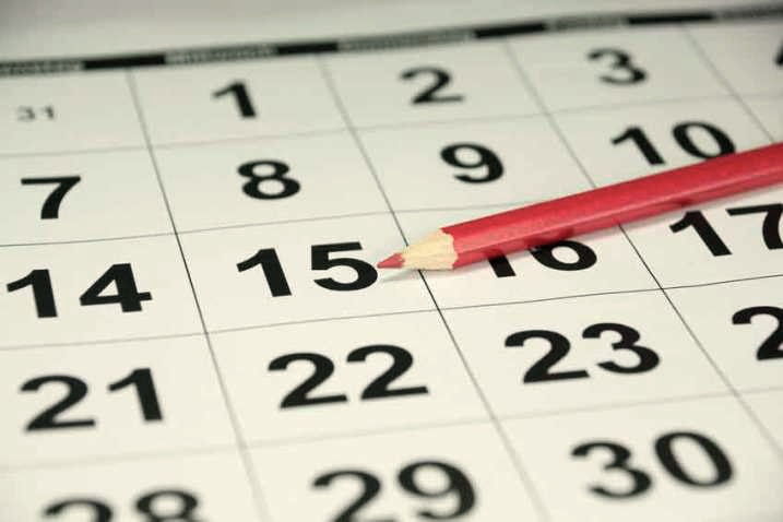 Ein Kalenderblatt mit hervorgehobenen Zahlen, und ein roter Bleistift zeigt auf den 15. Tag des Monats.