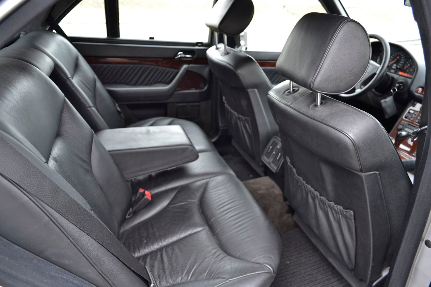 Einblick in das Interieur der Rücksitze eines Mercedes w140 mit schwarzen Ledersitzen und Armlehne