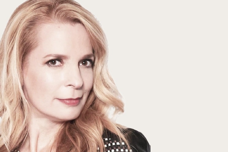 Nicole Y. Männ, eine Gastautorin bei Hiscox und eine Frau mit langen, welligen blonden Haaren, trägt eine schwarze Jacke mit silbernen Nieten im Schulterbereich.