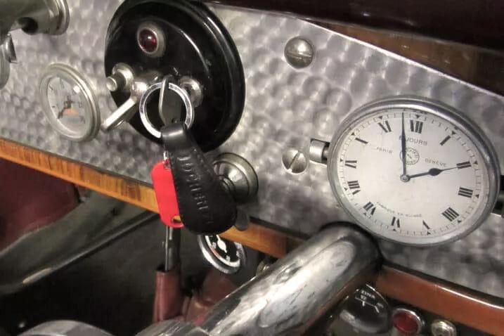 Klassischer Autoinnenraum mit Zündschloss, eingestecktem Schlüssel und rotem Anhänger.