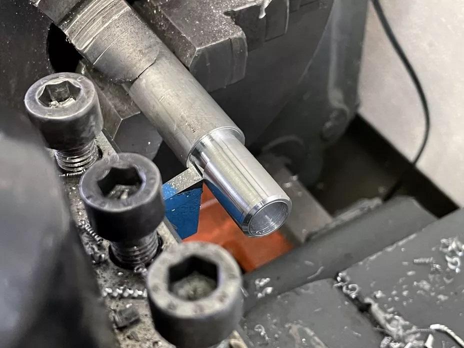 Nahaufnahme einer Drehmaschine, die ein zylindrisches Metallwerkstück bearbeitet.