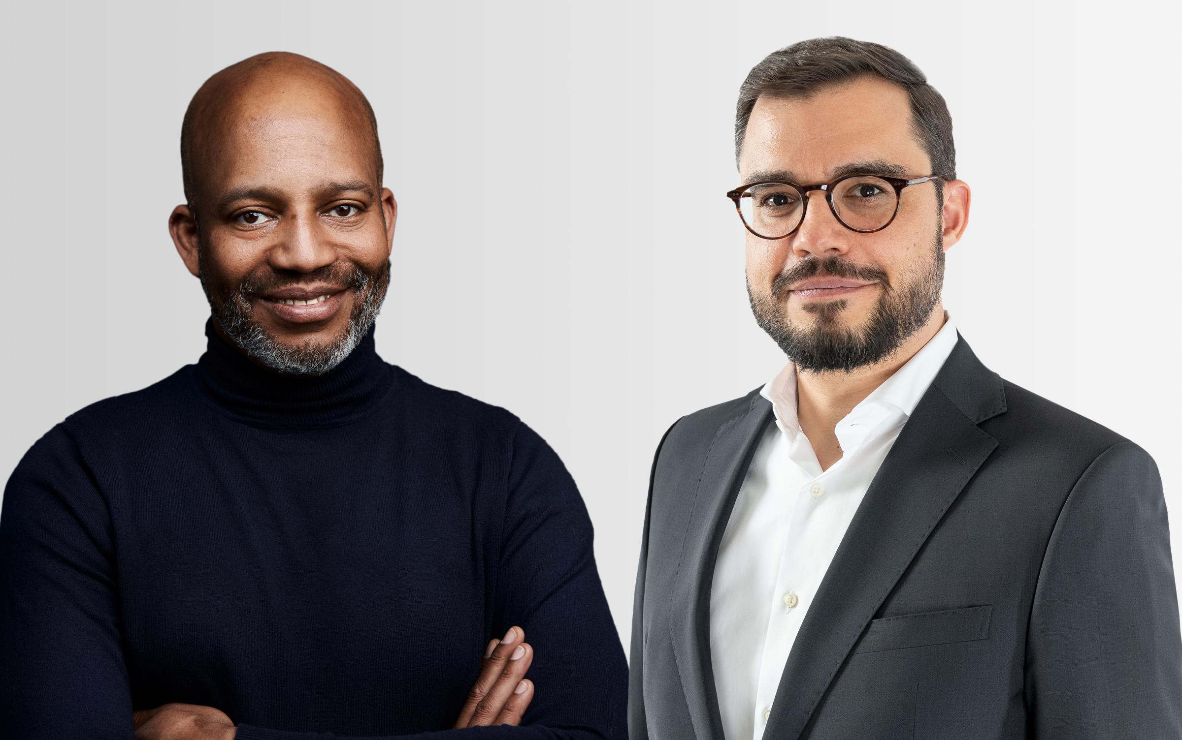 Utena Treves in schwarzem Rollkragenpullover und Markus Niederreiner in Anzug und Hemd stehen nebeneinander im Zeichen der Moojo Kooperation Gross C mit Hiscox