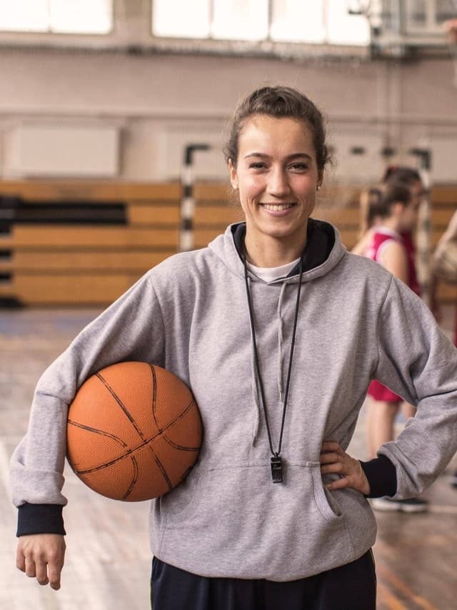 Vereinshaftpflichtversicherung von Hiscox: Junge Basketball-Spielerin blick lächelnd in die Kamera
