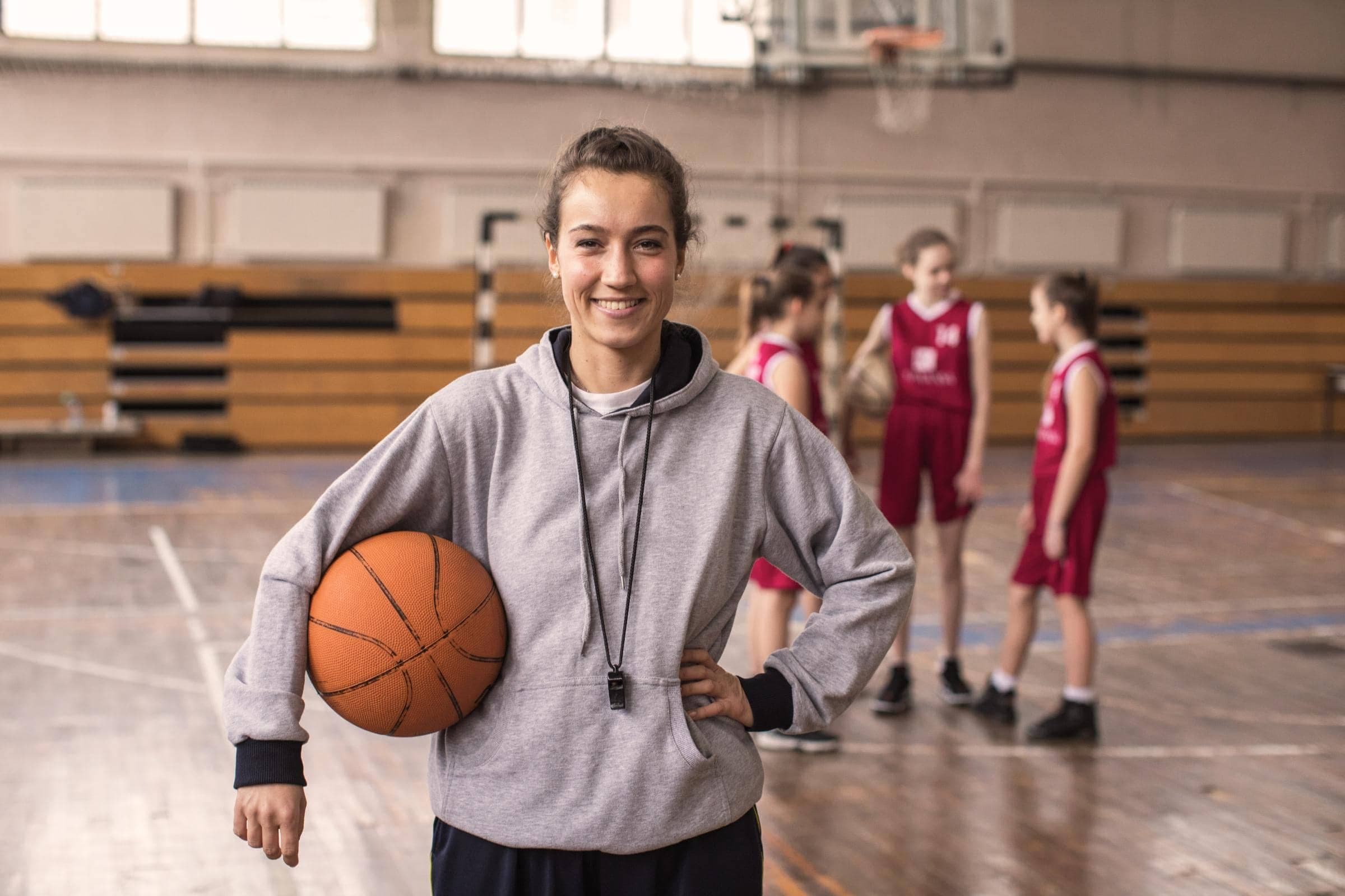 Vereinshaftpflichtversicherung von Hiscox: Junge Basketball-Spielerin blick lächelnd in die Kamera