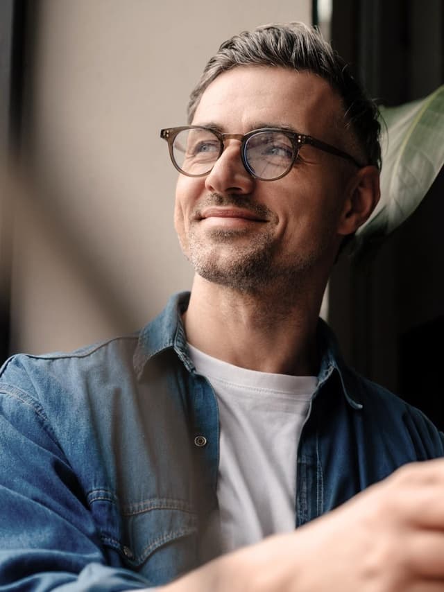 Versicherungen von Hiscox: Mann mit Brille blickt lächelnd in die Ferne