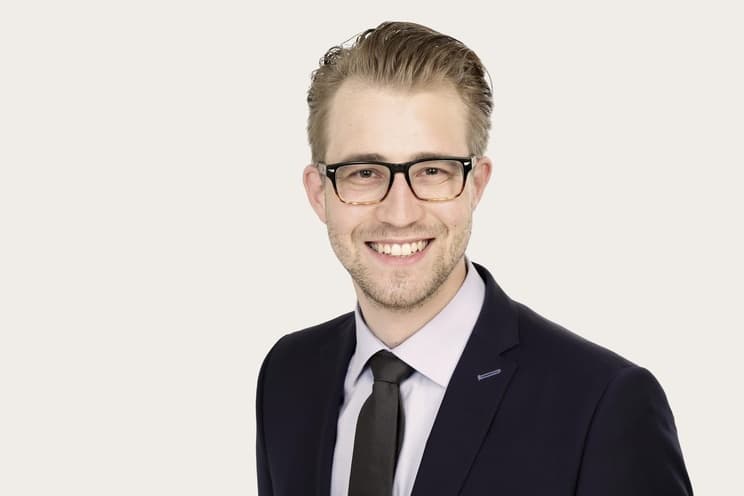 Ein Mann in Anzug mit Krawatte und Brille lächelt - Bastian Lutz, Sales & Development Underwriter Commercial Lines