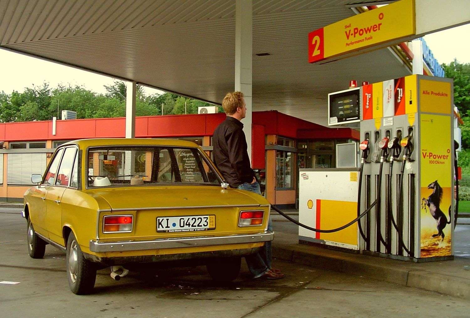 Goldener VW K70 L 1971 steht an einer Tankstelle und wird von Jens Tanz aufgetankt. Jens Tanz lehnt an Fahrzeug