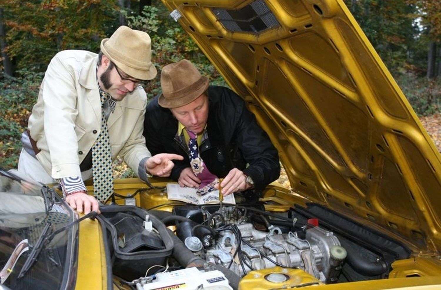 Jens Tanz blickt mit einem weiteren Mann in den offenen Motorraum des goldenen VW K70 L 1971