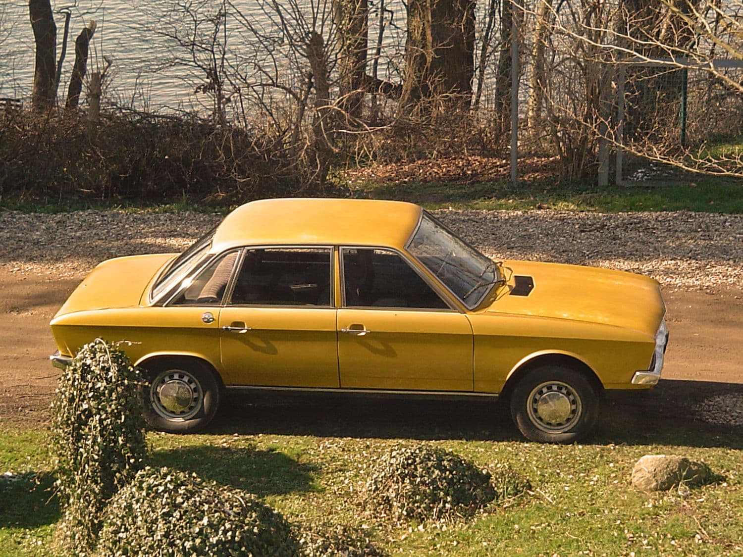 Ansicht eines goldenen VW K70 L 1971 von oben. Fahrzeug parkt auf einer Straße an einem See